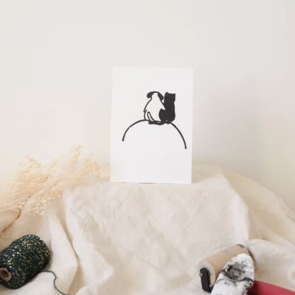 Linogravure noire et blanc d'un chat et un chien de dos se serrant